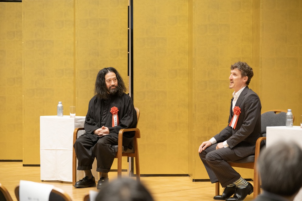 オープニング基調講演で話す又吉直樹氏とチャド・マレーン氏